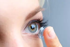 Close up of a woman placing a contact lens on her eye