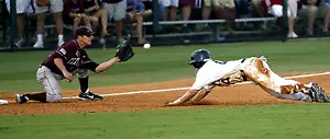 In a baseball game, a player slides towards a base while a fielder attempts to catch the ball.
