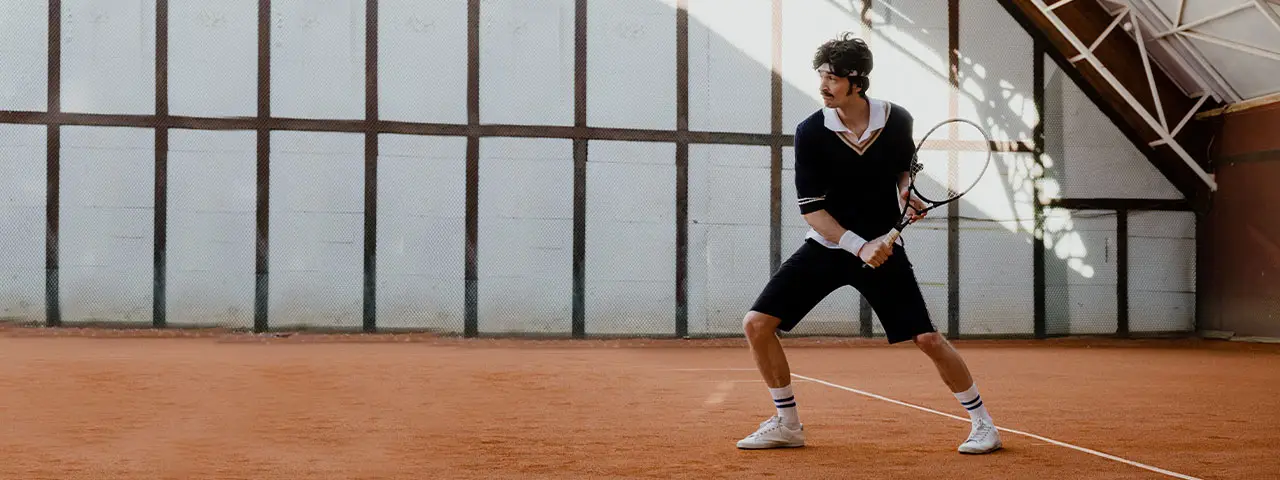 Man playing tennis in a black shirt and shorts