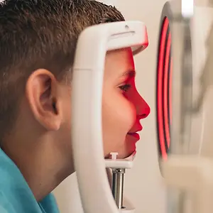 A young boy having his eyes examined by an eye doctor using an optical instrument.
