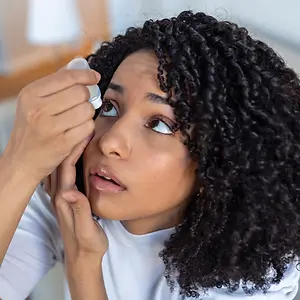 Woman puts eye drops in her eye