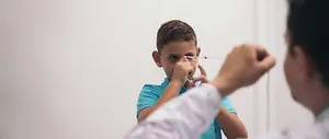 A young boy is getting his eye examined by a doctor, he has his eyes closed