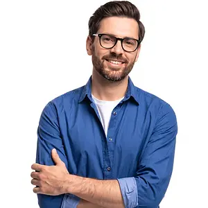 A smiling man with a beard wearing glasses and a blue shirt is posing for a picture.