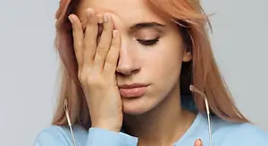 woman looking stressed and covering her face with her hand