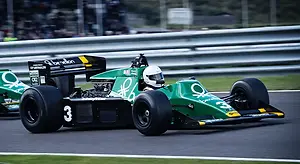 A green racing car with the number 3 on the front is driving on the track