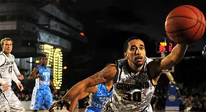 A basketball player wearing a Spartans jersey prepares to shoot the ball during a game.
