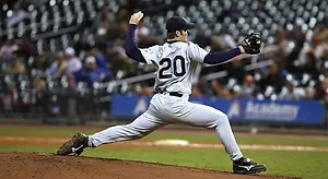 A baseball player with the number 20 on his jersey is pitching on the field at night.
