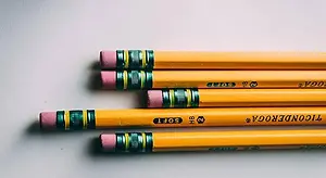 Four yellow pencils with pink erasers and green tips arranged in a row on a white background