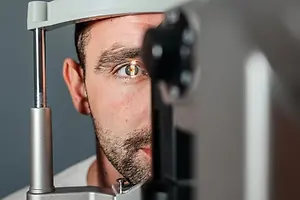 A man is having his eyes checked by a doctor using a machine