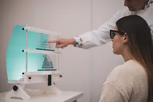 A man is pointing to a screen while a woman is watching in a medical examination room