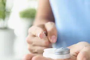 Close-up of hands holding a lens case and a lens.