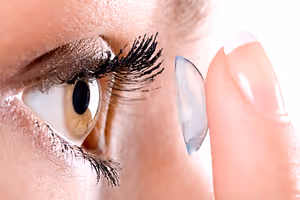A woman is touching her eye with her finger while wearing a contact lens