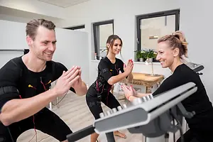 Three individuals are exercising, one of them is wearing a fitness belt, while the other two are holding each other's hands