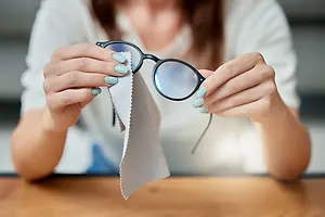 woman cleaning her glasses with a piece of cloth