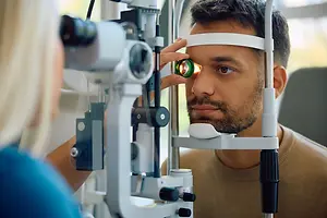Optometrist examining a man's eye with a slit lamp