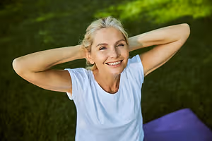 Smiling woman lying on grass with her hands behind her head