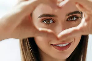 Smiling woman framing her eyes with her hands