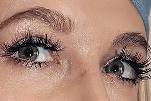 Close-up of a person's green eyes with long eyelashes and defined eyebrows