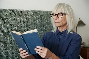 Older woman wearing eyeglasses and reading a book