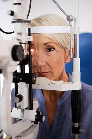 Woman wearing a blue blouse sitting in front of an ophthalmoscope device