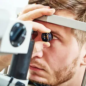 A man is looking into a microscope, probably in a laboratory.