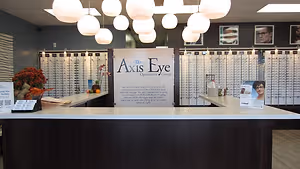Axis Eye Optometric group reception desk with the sign Axis Eye Optometric Group and a large display of glasses.