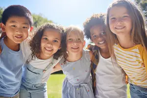 A group of children standing together and smiling in an outdoor area