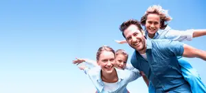 A man, woman, and two children are smiling and posing for a photo with a blue sky in the background