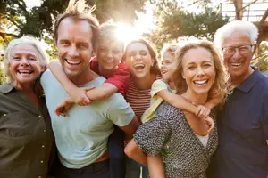 A family smiling and posing for a photo in a park with trees in the background