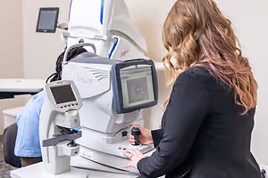 Woman examining a patient's eye using an eye examination machine
