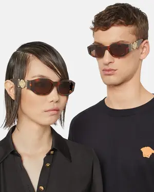 A man and a woman in black outfits are standing next to each other and wearing sunglasses.