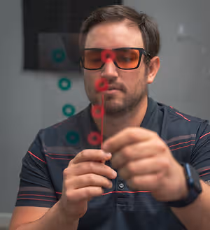 A man wearing sunglasses is looking at something with his hand on his chin.