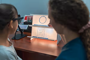 Two women using a microscope and a magnifying glass to look at an object on a stand
