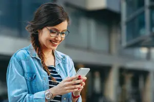 Happy woman looking at her phone while smiling