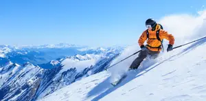 A skier in an orange jacket skiing down a snowy mountain slope