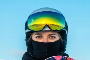 Snowboarder in goggles with reflection of sunset on the lenses
