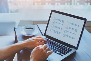 Person typing on laptop with coffee cup on desk