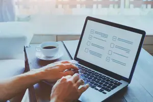 Person typing on laptop with coffee cup on desk