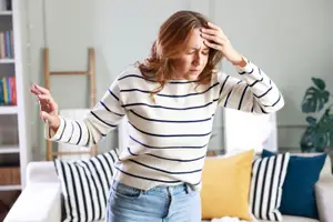 Woman in living room holding head and looking distressed