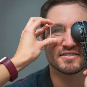 An adult male is having his eye measured for contact lenses by an optician