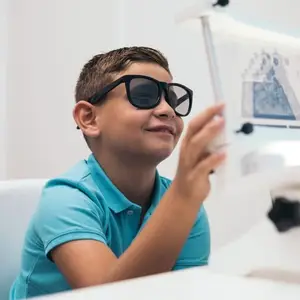 A boy wearing sunglasses and looking at an image on a white board