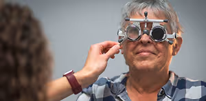 An older woman is adjusting her glasses with the help of a young woman in front of her.