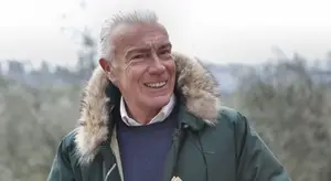 A man smiling for a photo in a park on a cloudy day
