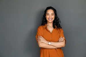 Portrait of a smiling woman with arms crossed in an office