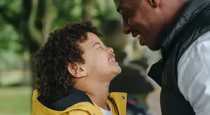 African American father and son smiling at each other outdoors in a park