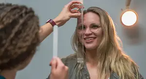 A woman smiling as a person measures her height with a ruler