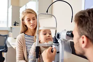 A little girl is getting her eyes checked by an optometrist