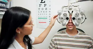 A man is getting his eyes checked by an optometrist wearing glasses in a clinic