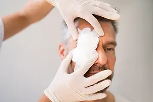 A doctor is treating a patient's eye with a bandage and a cotton ball