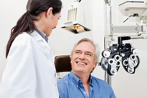 A smiling man having an eye exam with an optometrist